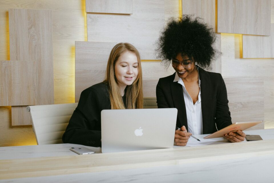 two women looking at screen using dynamics 365 for professional services and laughing